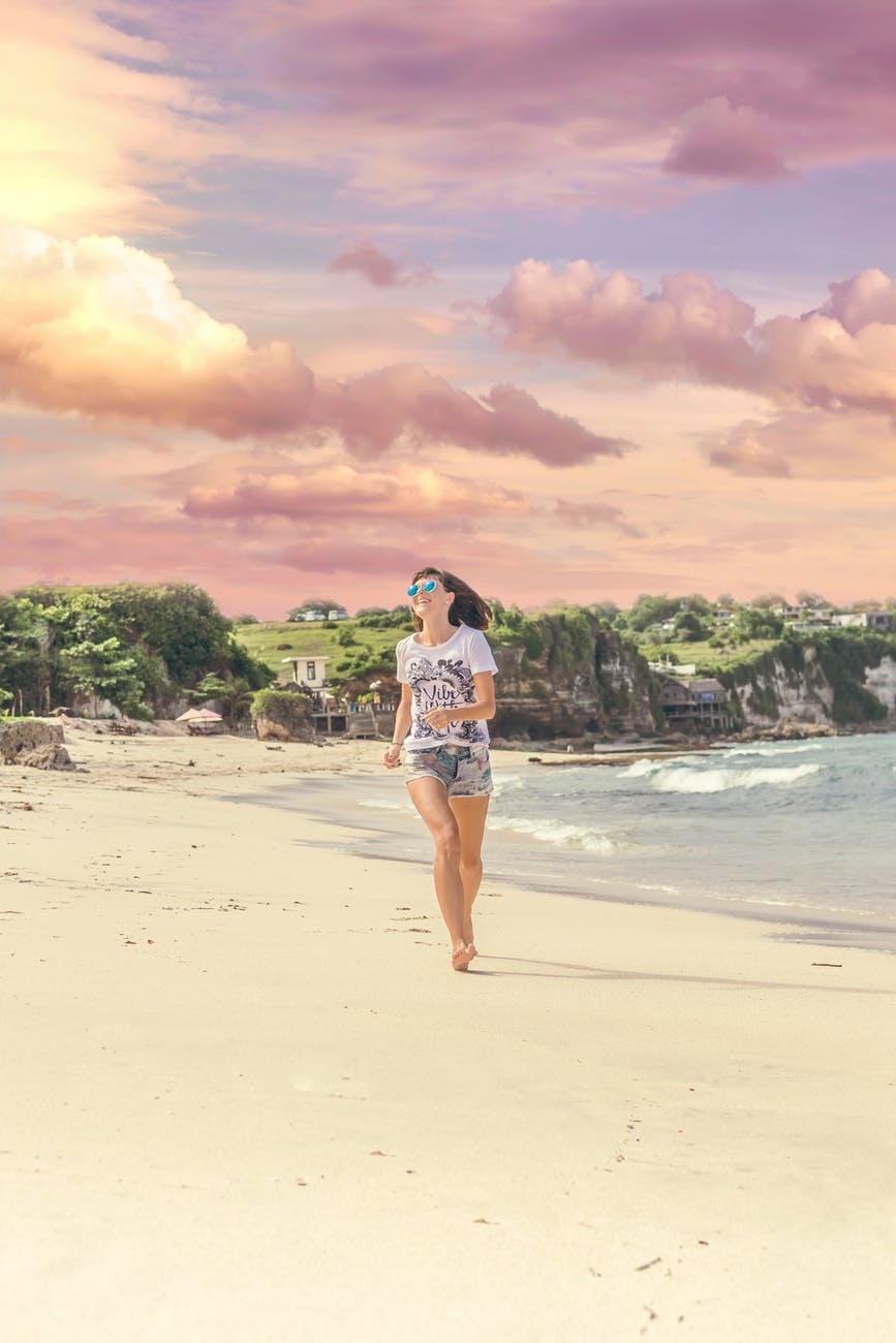 smiling woman walking barefood on seashore near houses