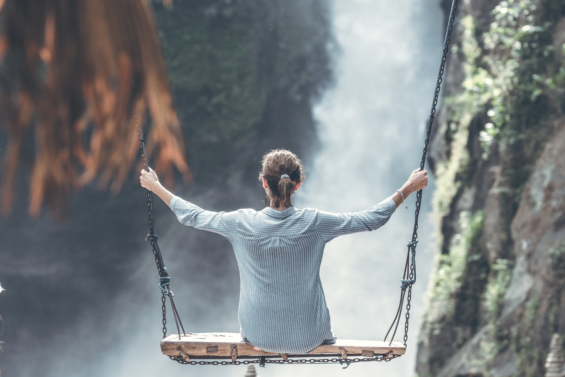 woman riding big swing in front of waterfalls