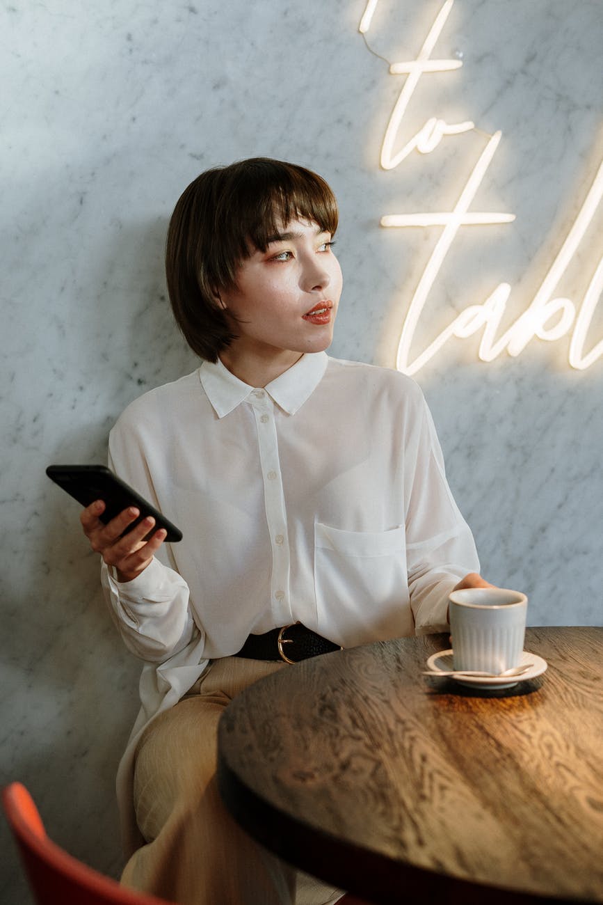 boy in white dress shirt holding black smartphone