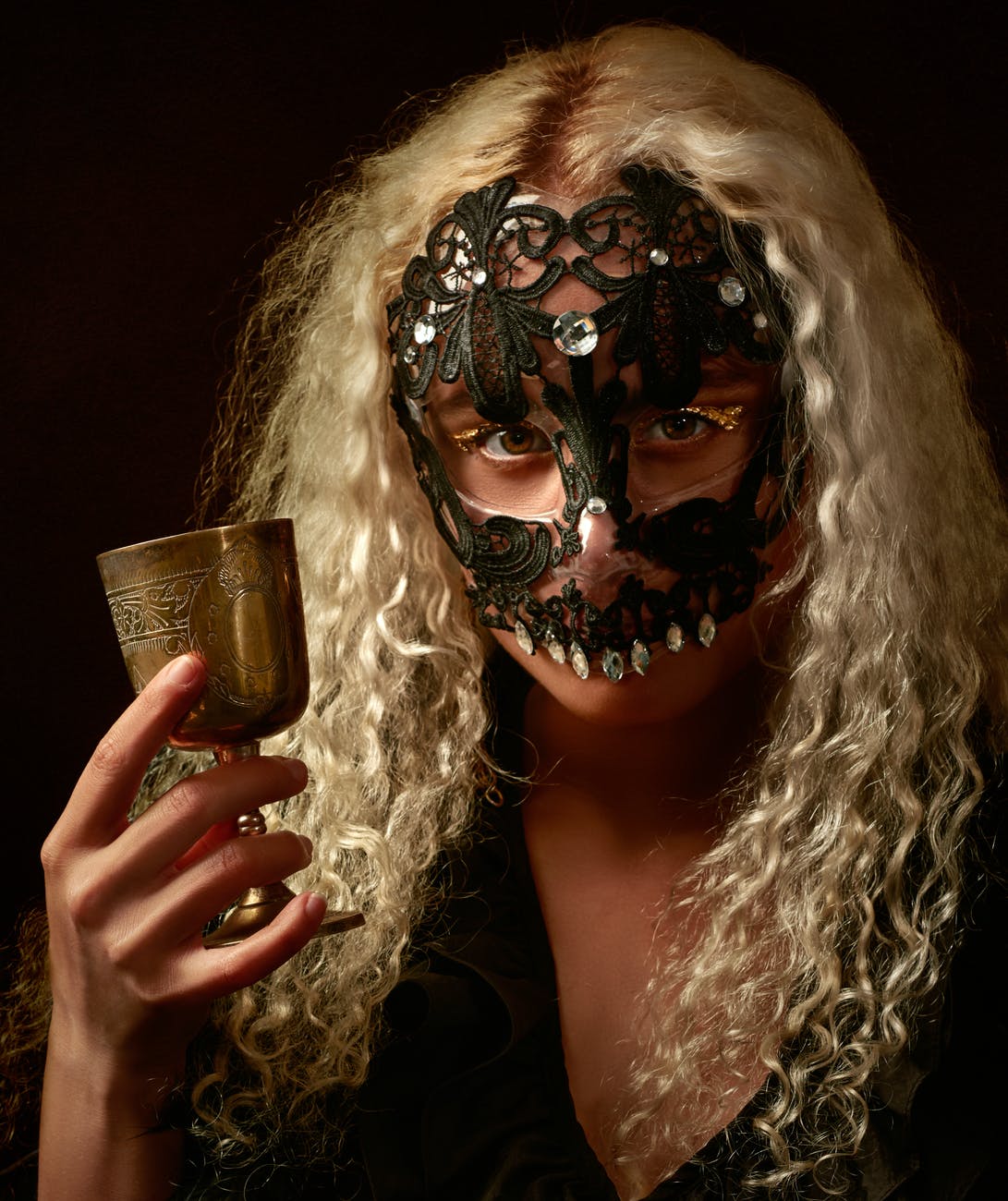 photo of person wearing masquerade mask while holding goblet