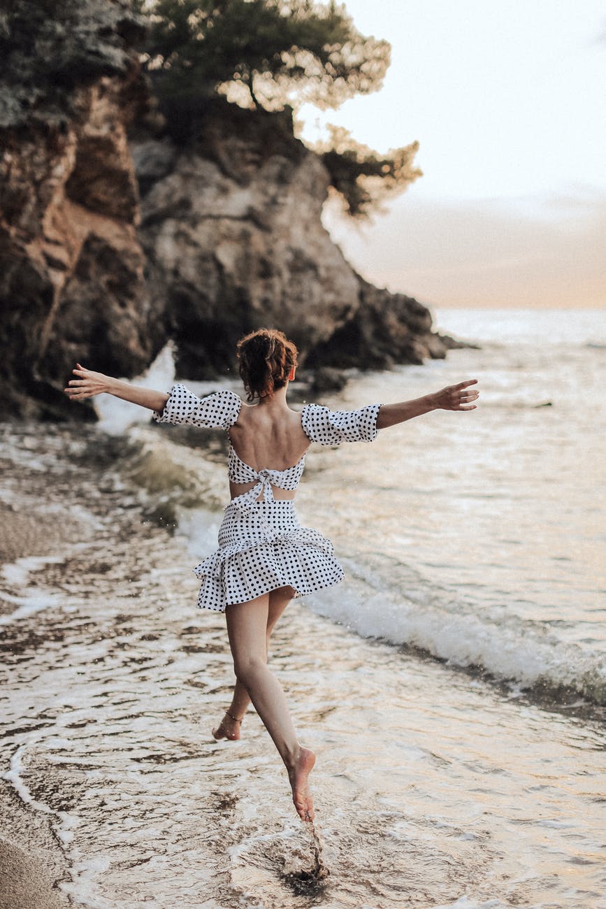 woman skipping through water on beach