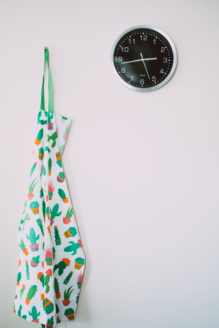 white and green cactus pattern apron near round gray analog wall clock