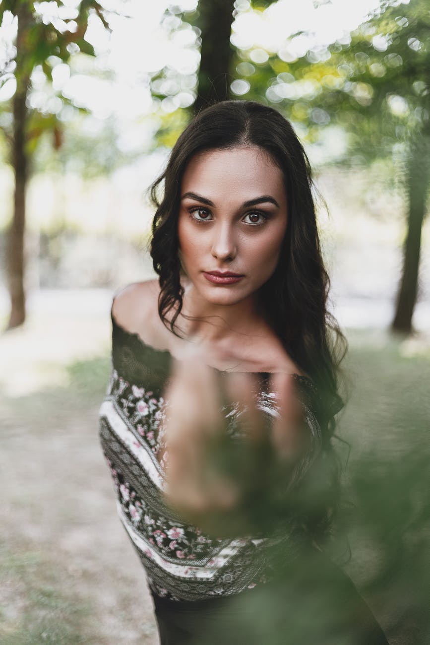 confident young woman reaching hand towards camera in park