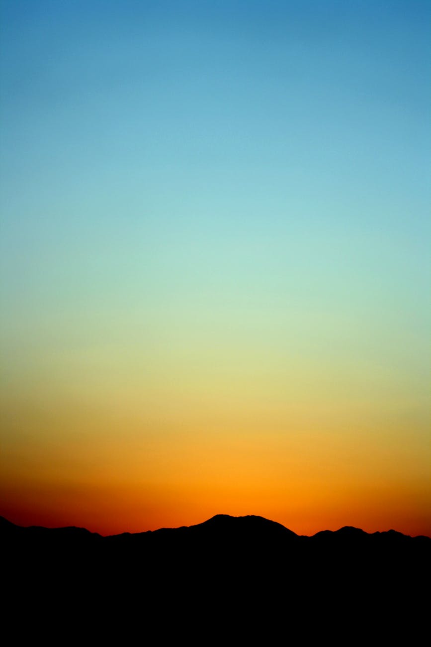 silhouette of mountain under orange and blue sky during sunset