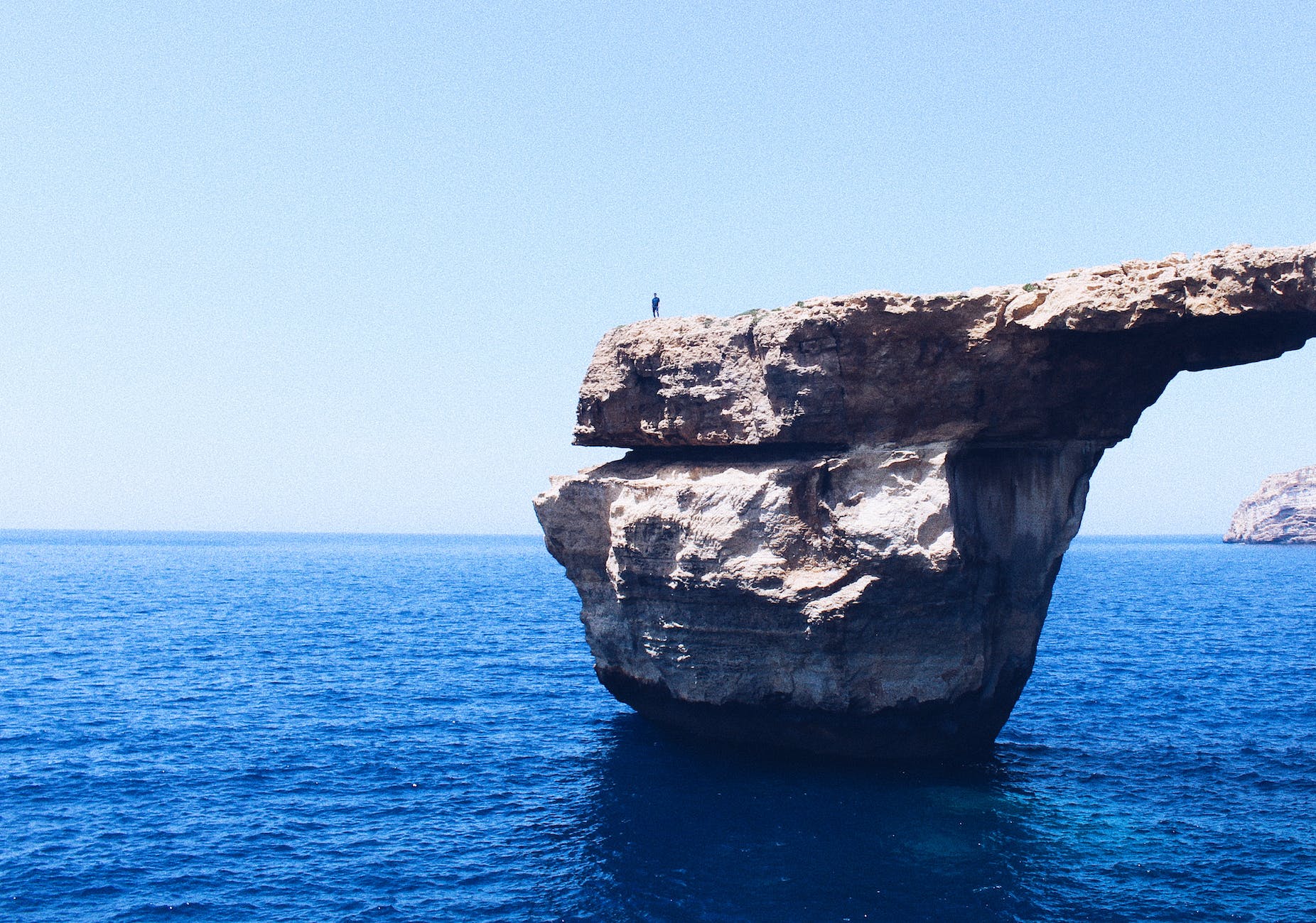 person standing on rock formation cliff